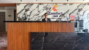 A reception desk with a marble wall, a logo, and a sign for Comfort Inn by Choice Hotel.