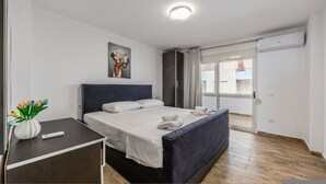 Une chambre d’hôtel avec un lit, une table de chevet, une télécommande, un vase avec des fleurs et un tableau au mur.