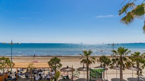 Un restaurant situé en bord de mer, avec une terrasse, des palmiers et une vue sur l’océan.