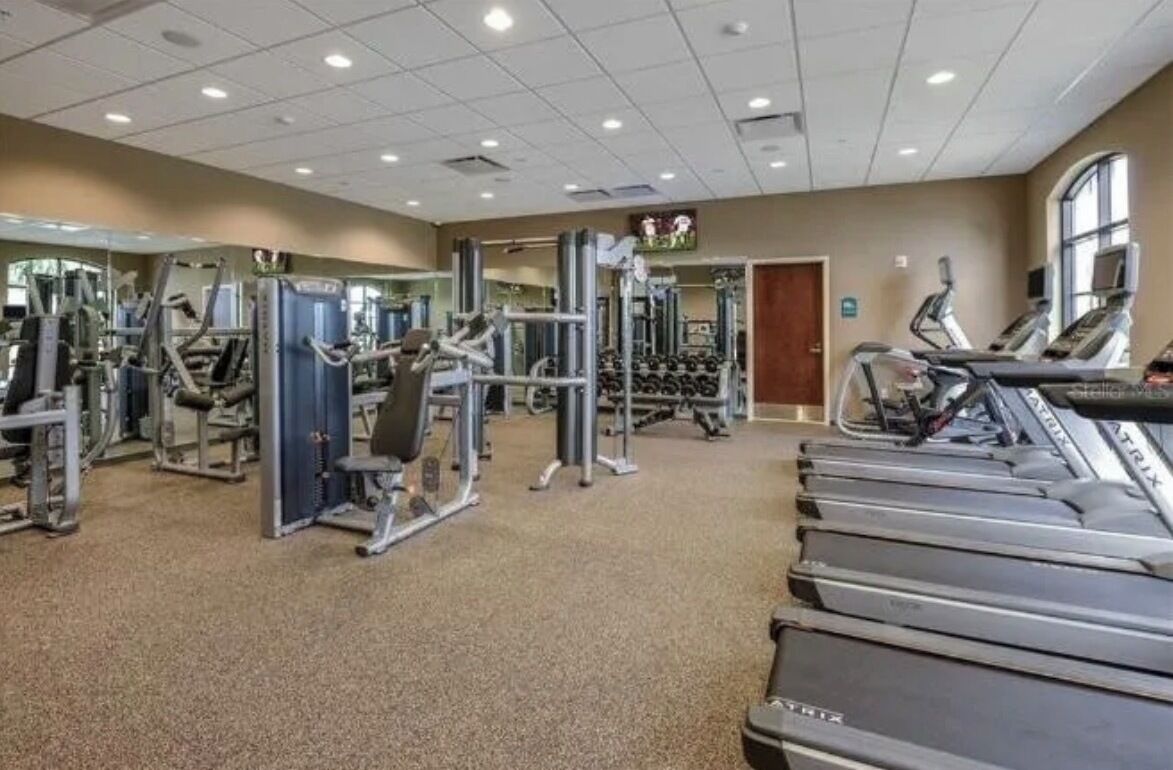 Une salle de sport équipée de tapis de course, d’appareils de musculation et de miroirs.