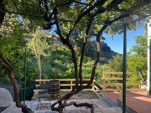 A rustic outdoor seating area with a wooden bench, a metal trash bin, and a stone pathway. - LA FINESTRA SUL MARE - LA FINESTRA SUL MARE (Marciana)