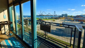 A balcony with a view of a roller coaster and a body of water.