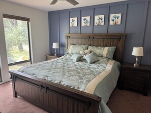 Un dormitorio con una cama grande, dos mesitas de noche, un ventanal y decoración floral en la pared.