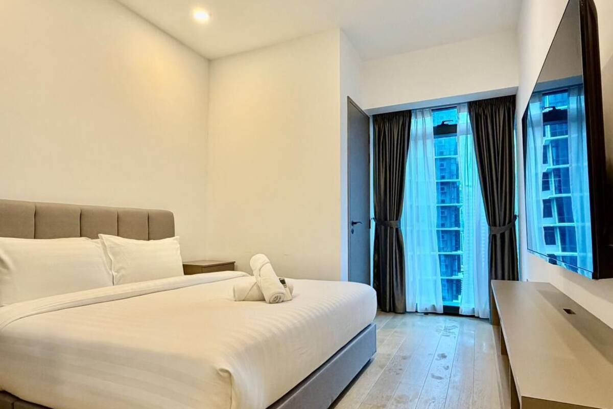 Habitación de hotel moderna con una cama grande, un escritorio y vistas a un edificio a través de la ventana.