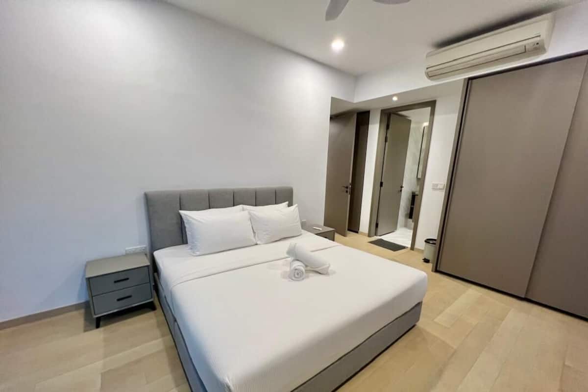 Una habitación de hotel moderna con una cama grande, una mesita de noche, un armario y un ventilador de techo.