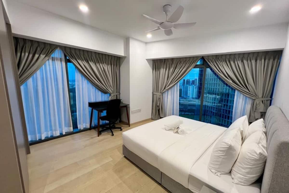 Una habitación de hotel moderna con cama, escritorio y ventanas amplias con cortinas.