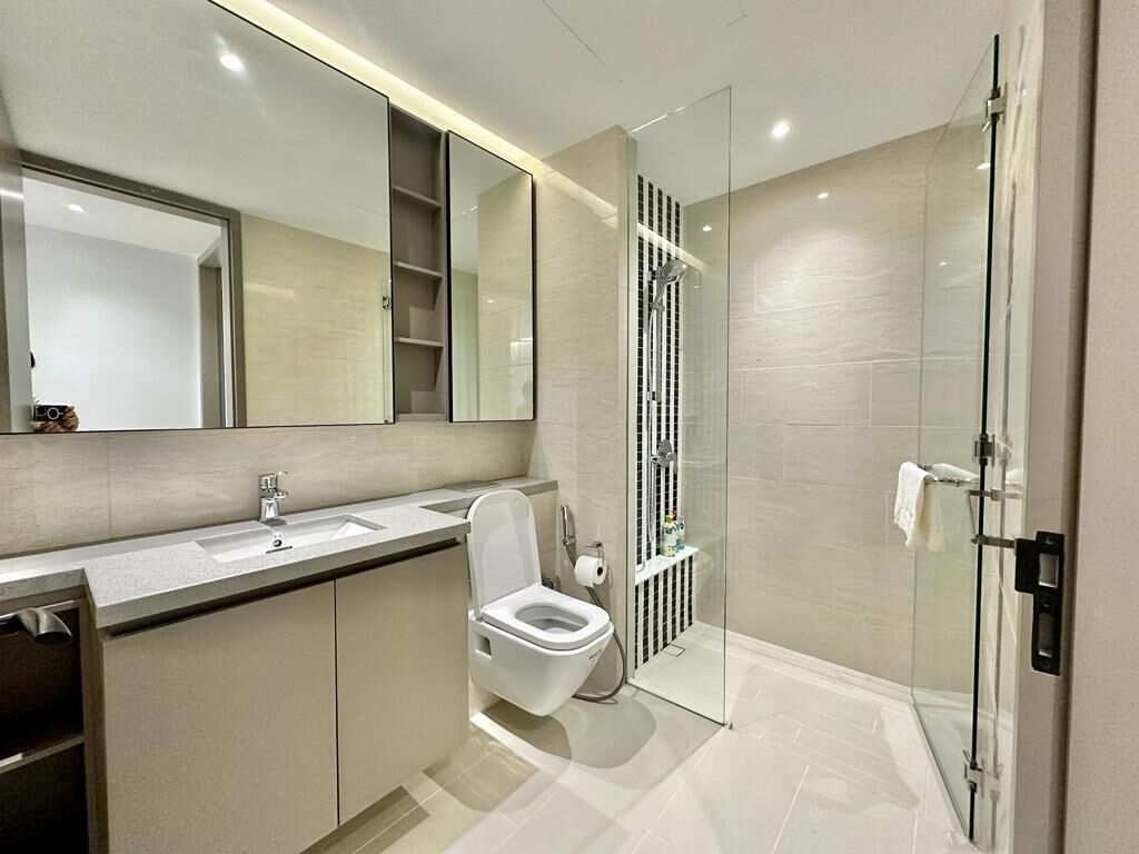 Un baño moderno con cabina de ducha de vidrio, inodoro y lavamanos.