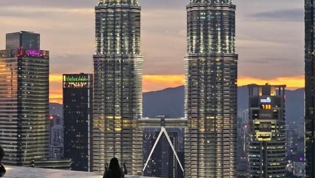 A view of the Petronas Twin Towers from an indoor pool area with a cityscape in the background.