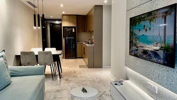 A modern living room with a sofa, dining table, chairs, a coffee table, and a TV mounted on a textured wall.