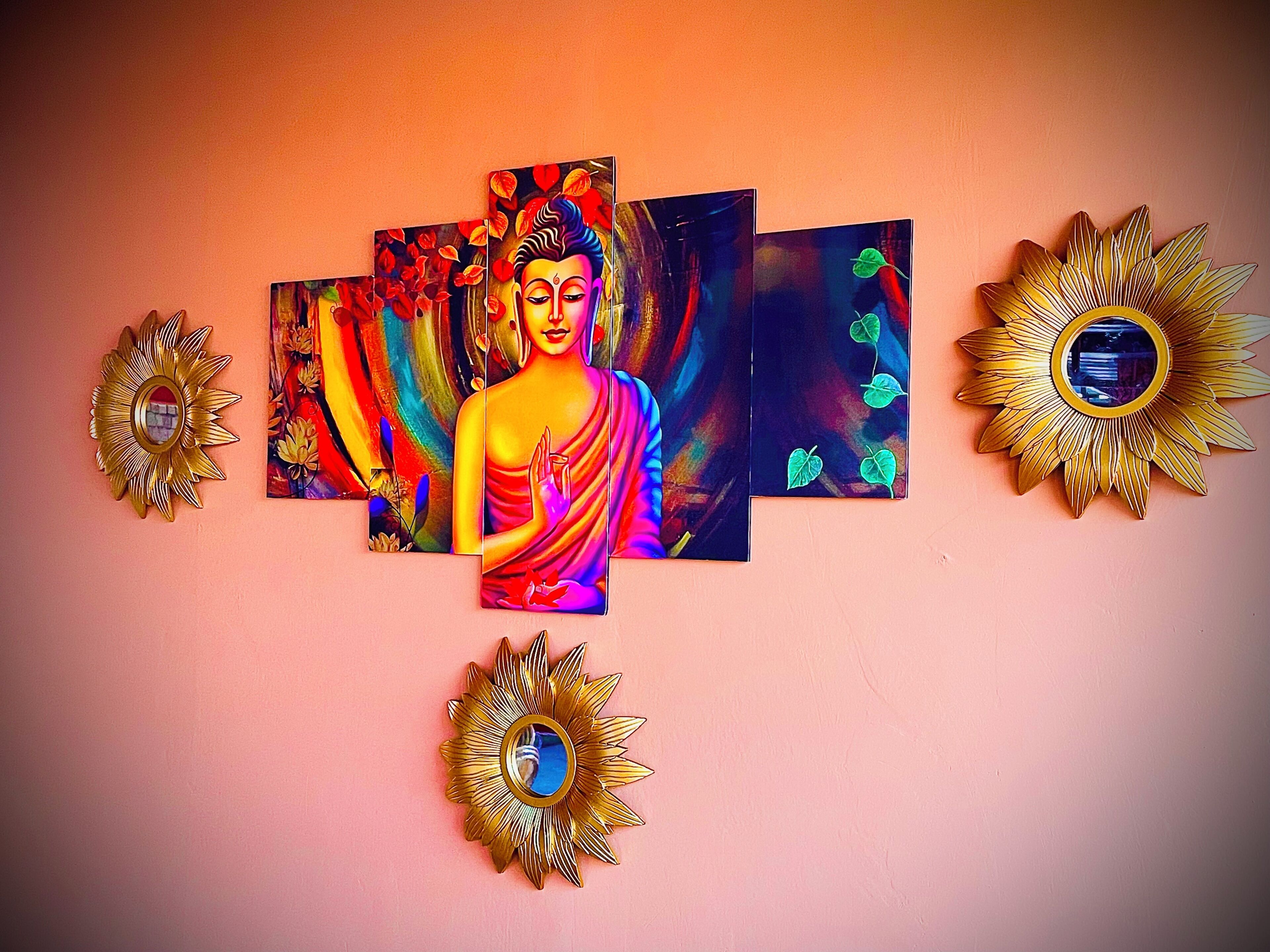 A wall with a Buddha painting and four sunburst mirrors.