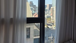 Een hotelkamer met een groot raam, gordijnen en een bed.