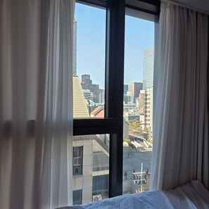 Ein Hotelzimmer mit großem Fenster, Vorhängen und einem Bett.