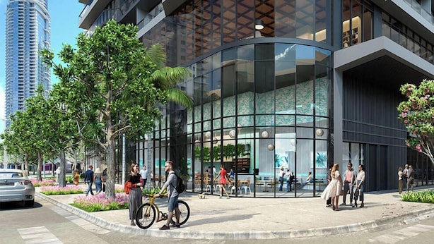 Een modern gebouw met een gebogen glazen gevel, terrasmeubels buiten en een fiets op de voorgrond.