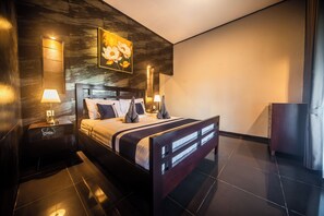A modern bedroom with a large bed, two bedside lamps, a painting, and a dark tiled floor. - 3BR Private Pool Tatiya Villa-Nusa Dua (Nusa Dua)