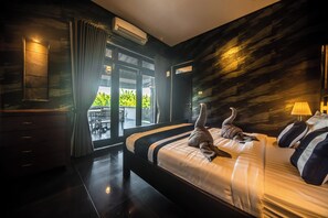 A modern hotel room with a large bed, a view through the glass door, and a dark wood wall. - 3BR Private Pool Tatiya Villa-Nusa Dua (Nusa Dua)