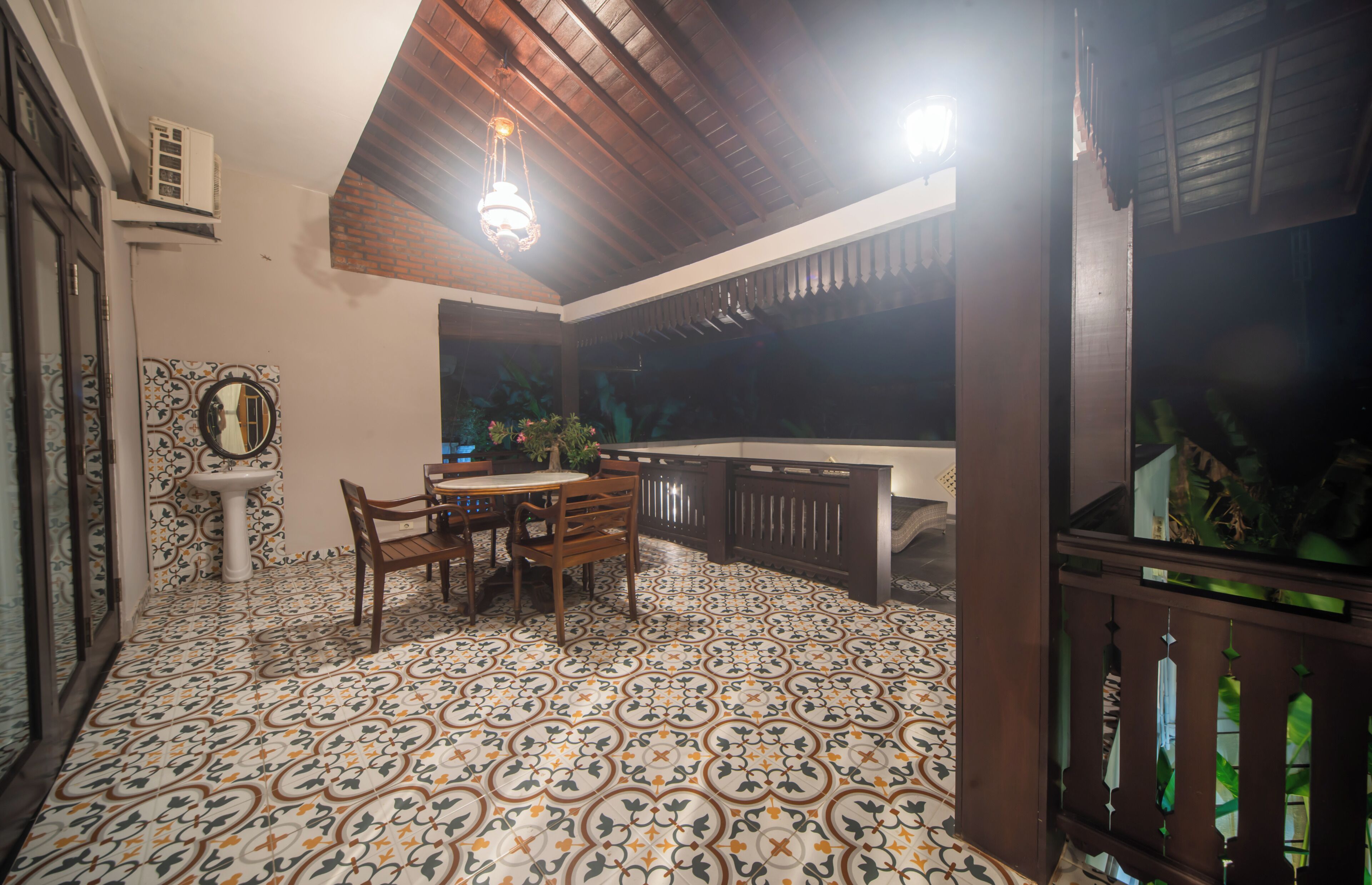 A room with a tiled floor, a dining table with chairs, a pedestal sink, and a large window.