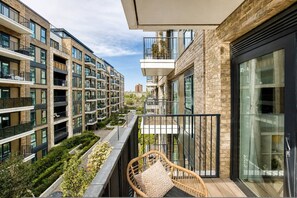 Een modern appartementencomplex met balkons, een tuin en een rieten stoel.