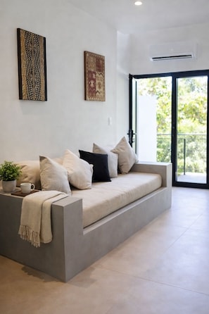 A modern living room with a grey sofa, a coffee table, and two wall art pieces. - Tamarindo 1 bedroom - 2 bathrooms 800 mts from the beach (Tamarindo)