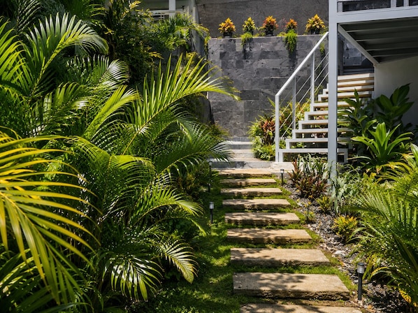 A stone staircase leading up to a building with a white railing, surrounded by lush greenery and potted plants. - Tamarindo 1 bedroom - 2 bathrooms 800 mts from the beach (Tamarindo)