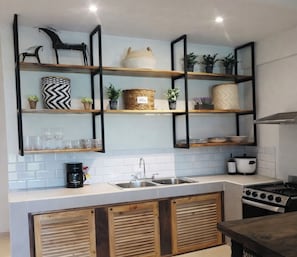 A kitchen with white tiled backsplash, wooden cabinets, a coffee machine, a sink, and a stove. - Tamarindo 1 bedroom - 2 bathrooms 800 mts from the beach (Tamarindo)