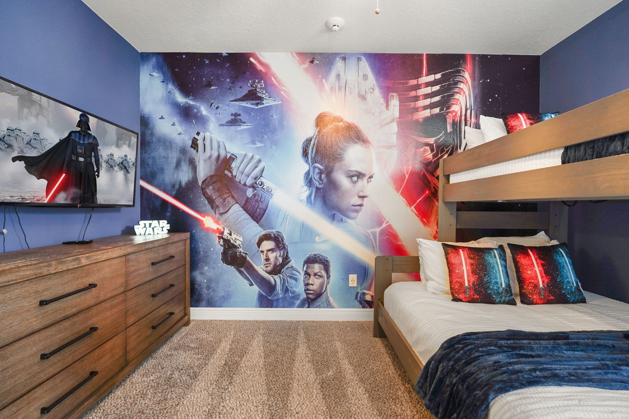A bedroom with a Star Wars themed wall mural, a bunk bed, and a wooden dresser.