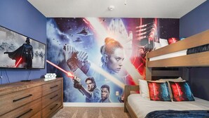 Ein Schlafzimmer mit Wandgemälde zum Thema Star Wars, einem Etagenbett und einer Holzkommode.