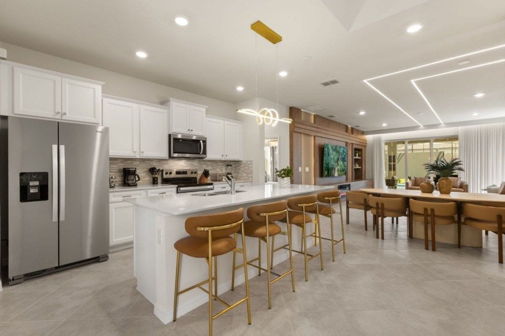A modern kitchen with white cabinets, stainless steel appliances, and a central island with bar stools.