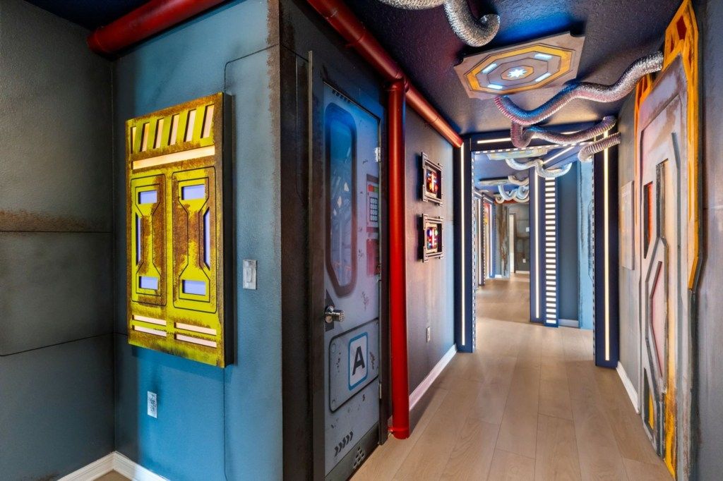 Un corridoio con porte, un tubo rosso e un soffitto dal design originale.