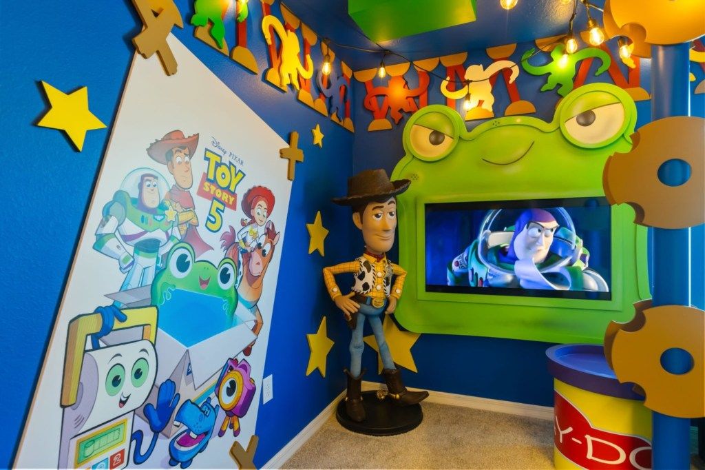 Ein Zimmer, das mit Elementen aus 'Toy Story 5' dekoriert ist, darunter ein großes Poster, eine Spielzeugfigur und ein Fernsehbildschirm.