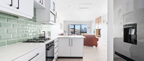 A modern kitchen with white cabinets, a green-tiled backsplash, and a stainless steel refrigerator.