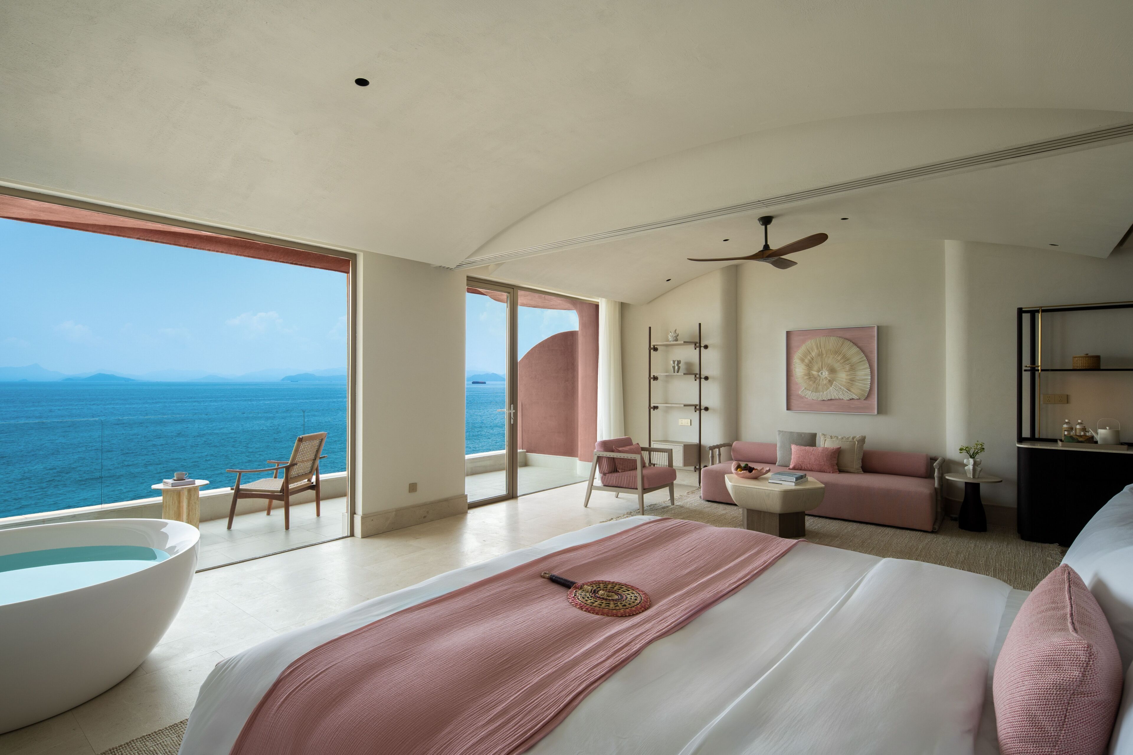 Un dormitorio amplio con una cama grande, un rincón de descanso, una bañera y vistas al océano.