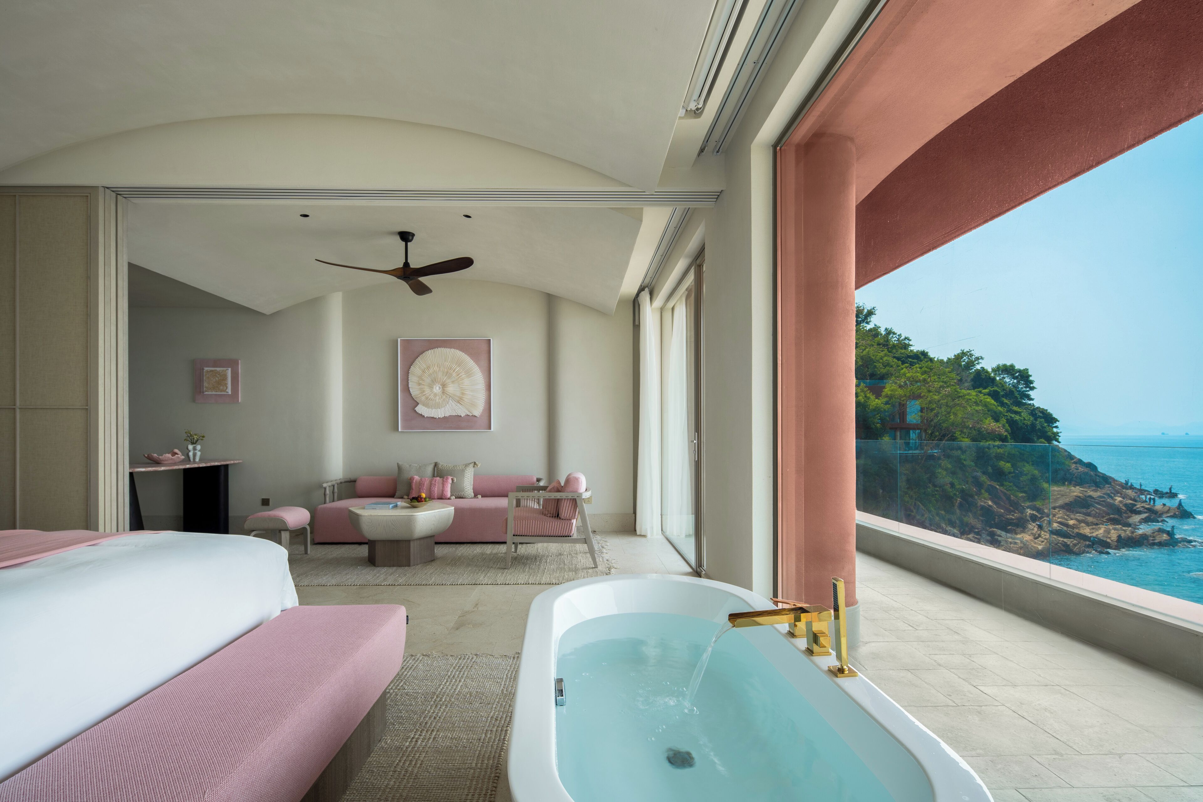 A bedroom with a large bathtub, a sofa, and a view of the ocean.