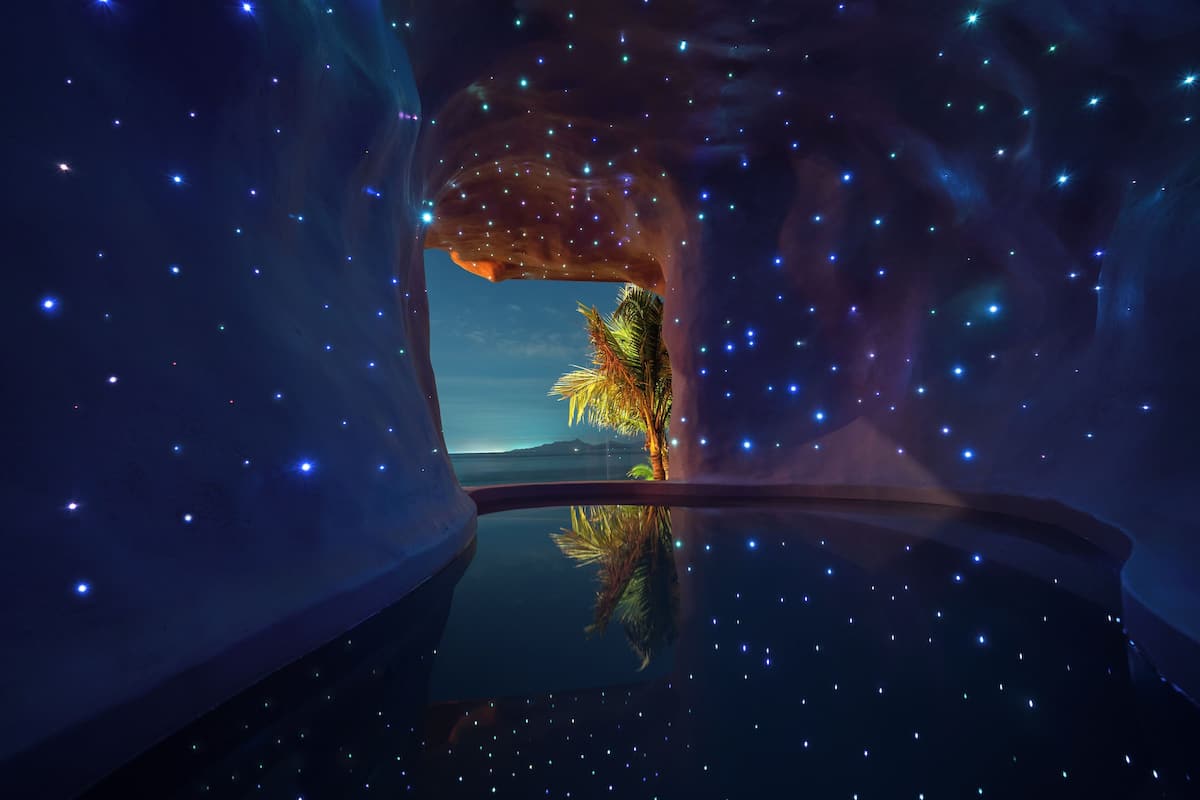 Cielo estrellado visto a través de una ventana, con el reflejo de una palmera.