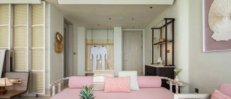 A modern bedroom with a pink bed, a fruit bowl, and a book on the bedside table.