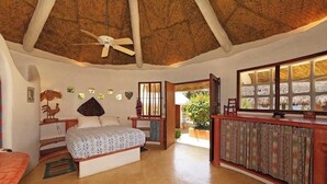 A bedroom with a bed, a ceiling fan, a nightstand, a dresser, and a window with a view of greenery. - Casa Rana Verde: Marvelous 3-bedroom villa with AC in vibrant Sayulita (Sayulita)