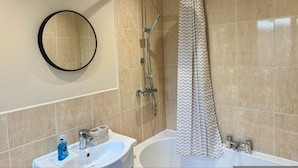 A modern bathroom with a bathtub, a shower, a sink with a mirror, and a toilet. - South Shields 3BR House Sleeps 6 Great for Group Stays (South Shields)