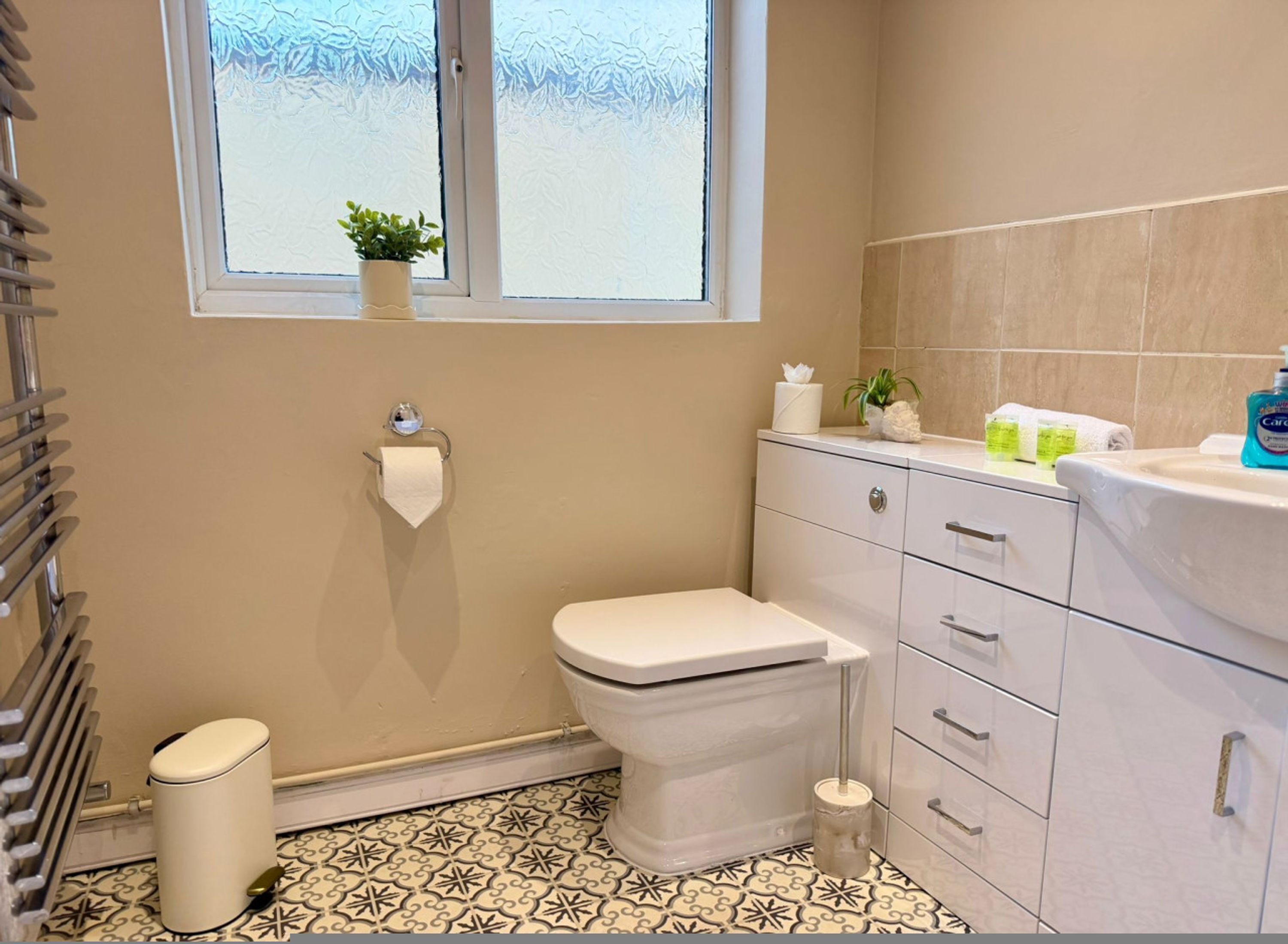 Een badkamer met toilet, wastafel en raam met plant.