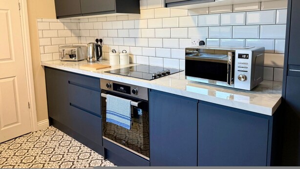 A modern kitchen with dark cabinets, a white countertop, a microwave, a toaster, and a dishwasher. - South Shields 3BR House Sleeps 6 Great for Group Stays (South Shields)