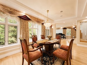 A formal dining room with a large table, chairs, and a chandelier.