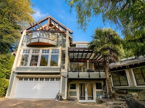 A modern two-story house with a garage, large windows, and a covered porch.