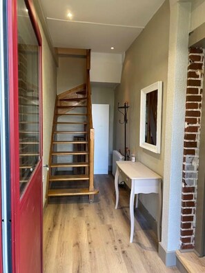 Eine Holzhandrail führt zu einer Zwischenebene, einem weißen Tisch und einer Ziegelwand.