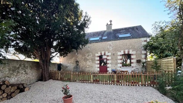 A stone building with a wooden fence, gravel ground, and two potted plants. - Maison classée 3 étoiles Parc du Manoir (Amboise)