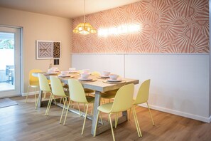 Un comedor con una mesa de madera, sillas amarillas y un papel tapiz estampado.