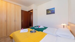 Ett hotellrum med två sängar, en garderob i trä, en tavla som hänger på väggen och en sänglampa.