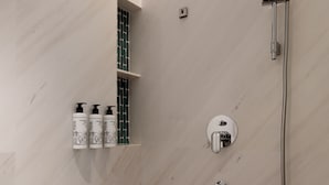 A bathroom with a shower, a towel rack, and a shelf with toiletries. - ChangZhou DaJiuDian (Changzhou)