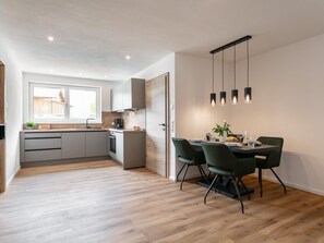 A modern kitchen with a dining area, wooden flooring, and pendant lighting. - Modern holiday apartment with sun terrace (Reith im Alpbachtal)