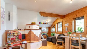 A cozy children's play area with a colorful foam mat, a wooden play structure, and a bookshelf filled with toys and books. - Vacation apartment with a wide view & garden (Brixen)