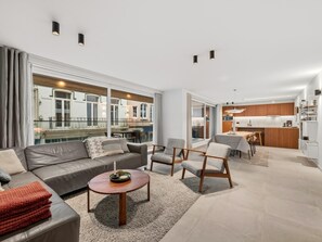 Ein modernes Wohnzimmer mit einer Couch, Sesseln, einem Couchtisch und Blick auf die Stadt.