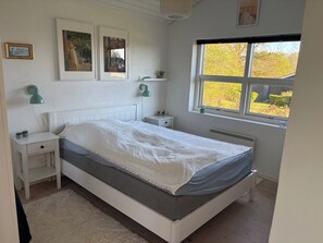 Een slaapkamer met een bed, nachtkastjes, een raam en decoratieve wandkunst.