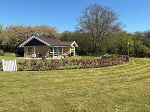 A house with a covered porch, a lawn, and a hedge. - Lovely, secluded holiday home near beach (Sydals)